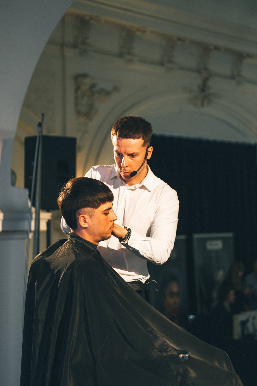 Vilis Sliacky s náhlavným mikrofónom strihá modela na pódiu Barberlogy v Olomouci