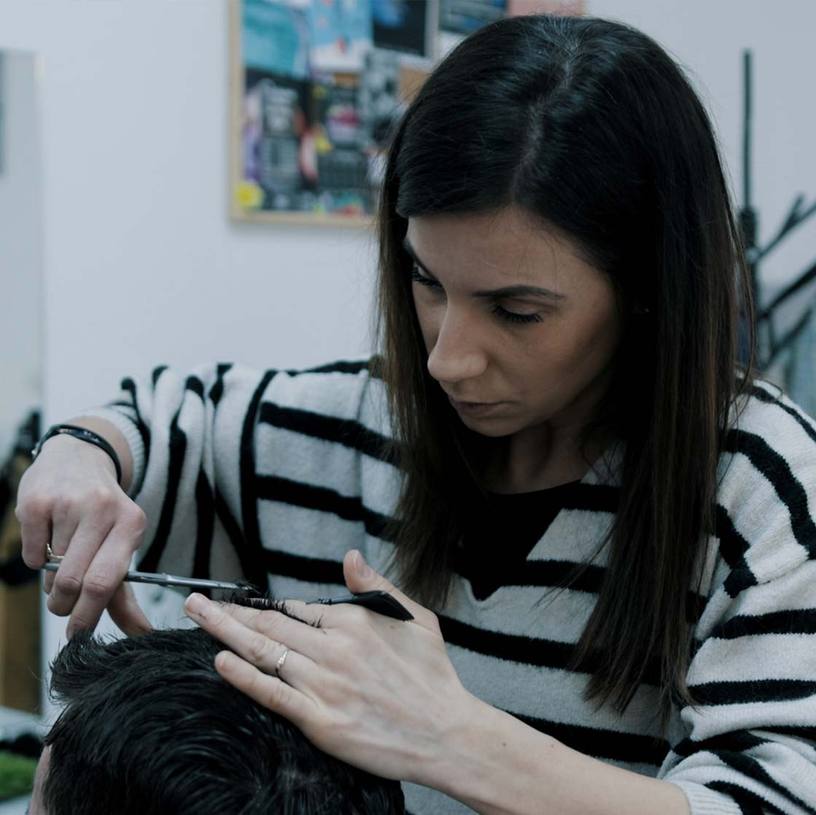 Ivana strihá klienta nožnicami a hrebeňom